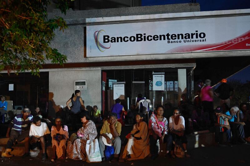 People get ready to spend the night outside a bank in Maracaibo, Zulia State, Venezuela on July 22, 2019 to collect their pensions the next day, as parts of the country, including the capital Caracas, were hit by a massive power cut. The lights went out in most of Caracas while people in other parts of the country took to social media to report the power had gone out there too. The state-owned power company CORPOELEC only reported a breakdown affecting sectors of Caracas. / AFP / Federico PARRA
