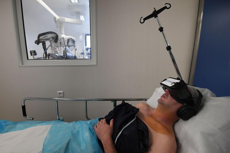A patient wearing a virtual reality headset received a local anaesthesia by an hypnotherapist anaesthetist; before a surgery, at the Rhéna Clinic on October 25, 2018 in Strasbourg, eastern France. HypnoVR, founded in 2016 by two anaesthetists and an entrepreneur, provides software and virtual reality headsets allowing the hypnotherapist to treat several patients. / AFP / Frederick FLORIN
