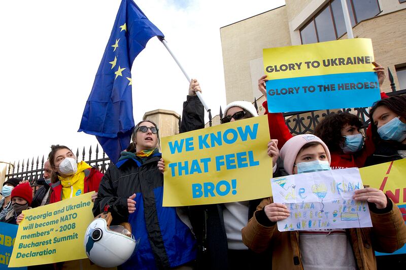 Activists hold an EU flag and posters as they gather in support of Ukraine at the Ukrainian embassy in Tbilisi, Georgia. AP