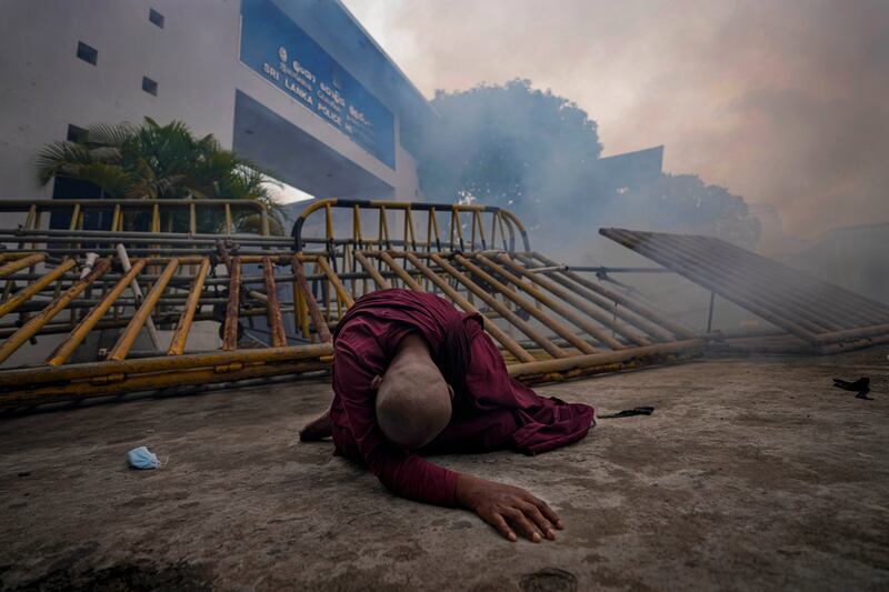 A Buddhist nun falls next to a barricade after inhaling tear gas during a protest outside police headquarters in Colombo, Sri Lanka. AP Photo