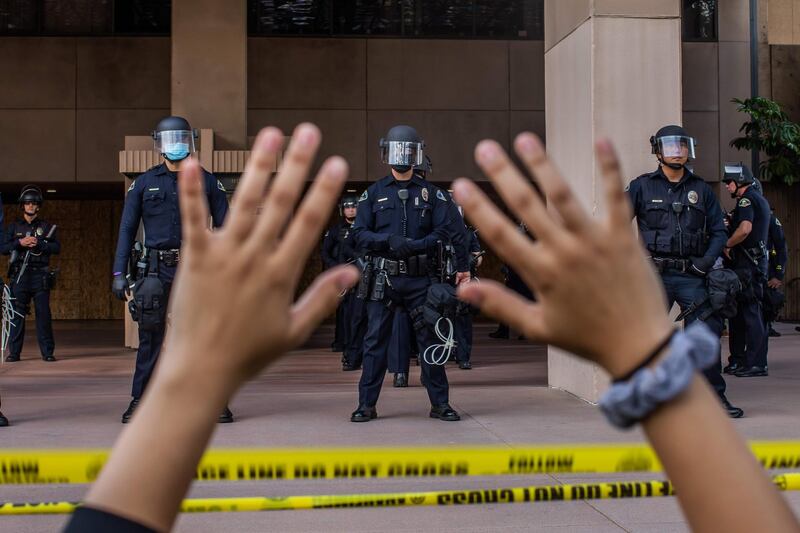 A demonstrator holds her hands up while she kneels in front of the Police at the Anaheim City Hall in Anaheim, California, during a peaceful protest over the death of George Floyd.  AFP