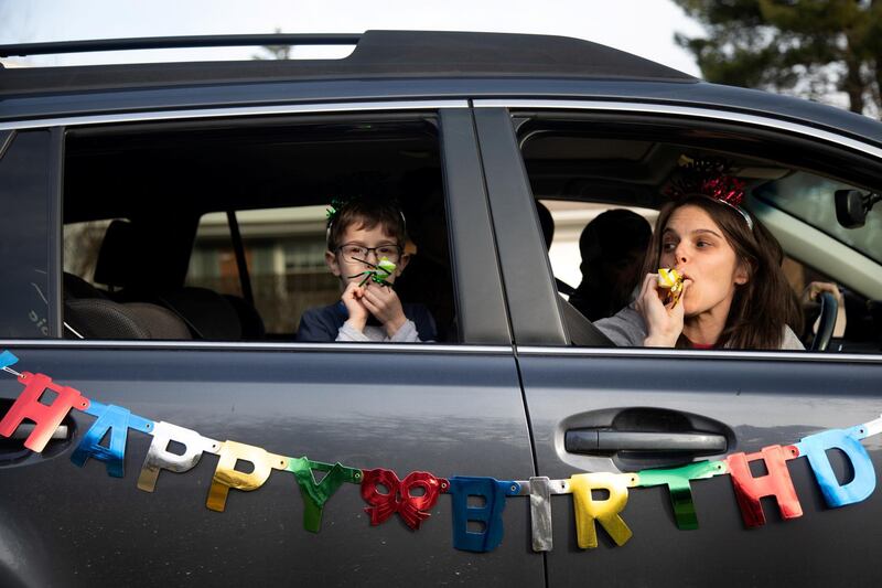 Dana Baer and her son Jacob Baer wish Avery Slutsky a happy sixth birthday from their car during a drive-by birthday celebration as they maintain social distance amid an outbreak of coronavirus disease (COVID-19) across the country in West Bloomfield Township, Michigan, U.S.  REUTERS
