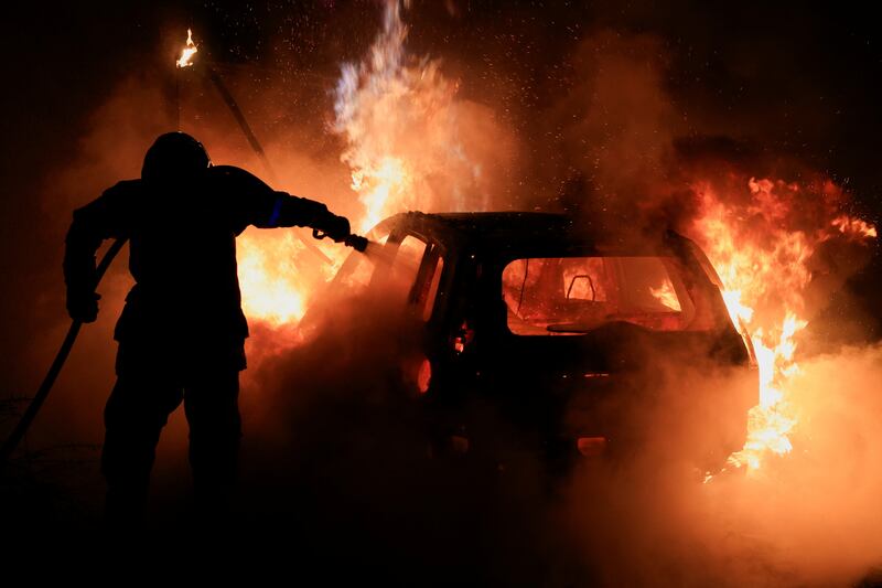 Firefighter works to extinguish burning car amid rioting in Tourcoing, France. Reuters