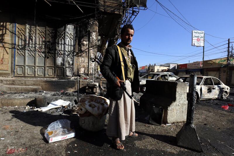 An armed Yemeni stands near destroyed vehicles at a street leading to the residence of Yemen’s ex-president Ali Abdullah Saleh a day after Houthi militants killed him, in Sana’a, Yemen. Yahya Arhab / EPA