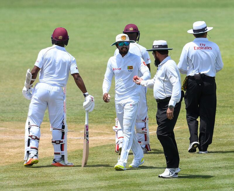 Dinesh Chandimal (C) of Sri Lanka receives the ball from umpire Aleem Dar (2C) during day 3 of the 2nd Test between West Indies and Sri Lanka at Daren Sammy Cricket Ground, Gros Islet, St. Lucia, on June 16, 2018. / AFP / Randy Brooks
