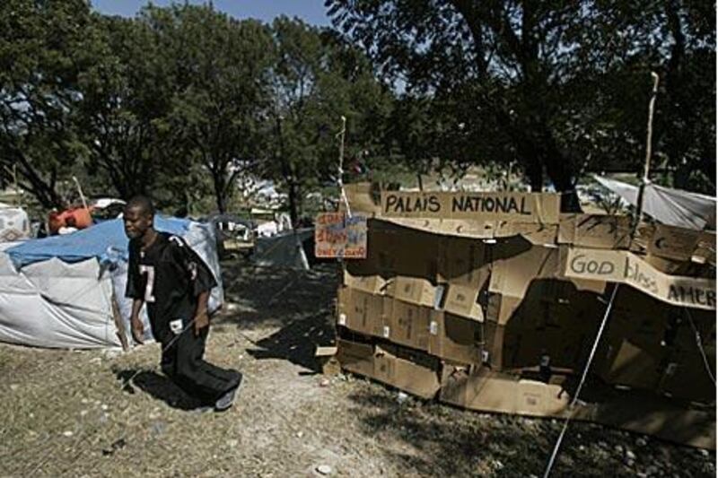 A man walks by a tent made of cardboard boxes with the sign "National Palace" in the Delmas 40 refugee camp for earthquake survivors in Port-au-Prince.