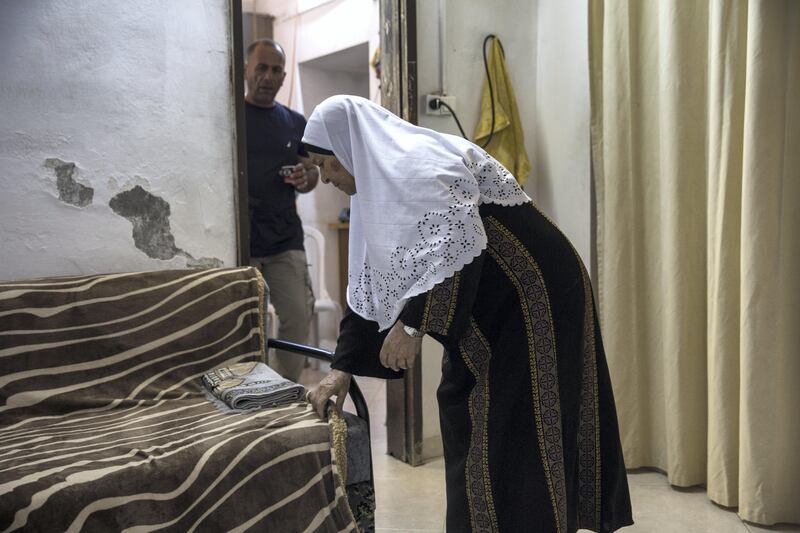  Mohamed Shamasneh watches his mother Fahima as she  fixes the blanket covering her sofa after she prayed in her tiny basement  home in the East Jerusalem neighborhood of Sheik Jarrah on August 11,2017.

When thehamasne family first moved into their home  in the 1960s, East Jerusalem was controlled by Jordan and their monthly rent was paid to  Jordanian authorities but since  Israel annexed East Jerusalem in 1967, the Shamasne family has paid their rent to Israel's general custodian in order to remain in the building.
The family claims that their payments were suddenly rejected in 2009 , and they were informed that the property had been claimed by Israeli Jews whose ancestors had lived there decades previously.Although the family has spent years fighting to remain in the home , the Israeli high court has ruled that the family must evacuate the home before August 9. (Photo by Heidi Levine for The National).