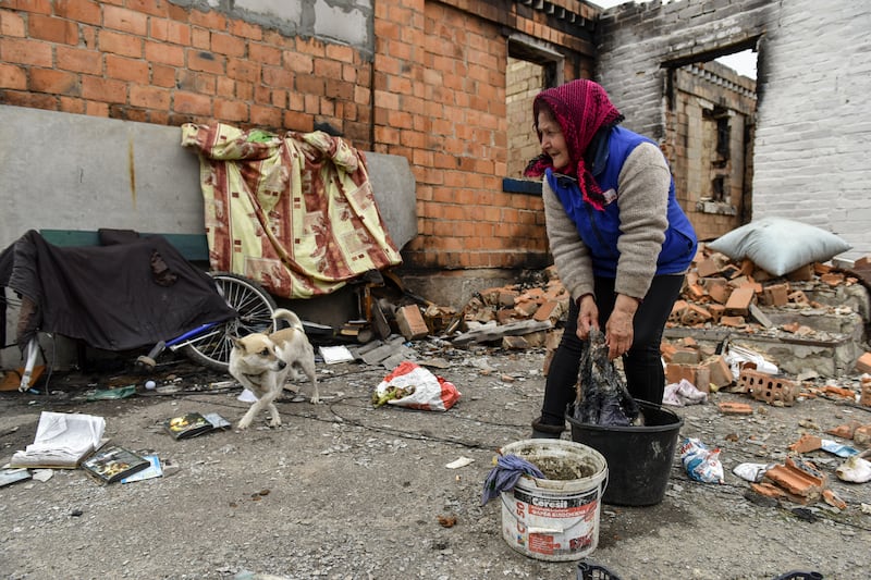 A woman washes clothes in the yard of a ruined house in Andriivka. EPA