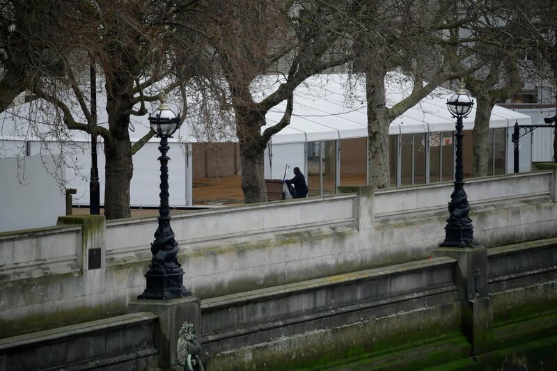 A worker walks past a newly built structure in the grounds of St Thomas' Hospital in central London. For most people, the new coronavirus causes only mild or moderate symptoms, such as fever and cough. For some, especially older adults and people with existing health problems, it can cause more severe illness, including pneumonia. AP Photo