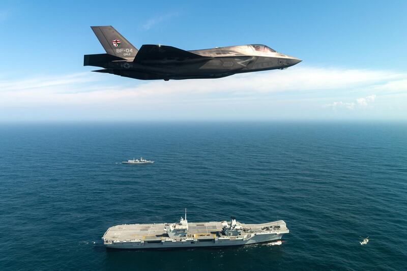 PORTSMOUTH, ENGLAND - SEPTEMBER 26: In this handout image provided by the Ministry of Defence, An F-35B fighter jet flies over HMS Queen Elizabeth on September 26, 2018 in Portsmouth, England.  Two F-35B Lightning II fighter jets have successfully landed onboard HMS Queen Elizabeth for the first time, laying the foundations for the next 50 years of fixed wing aviation in support of the UKs Carrier Strike Capability.
Royal Navy Commander, Nathan Gray, 41, made history by being the first to land on, carefully manoeuvring his stealth jet onto the thermal coated deck. He was followed by Squadron Leader Andy Edgell, RAF, both of whom are test pilots, operating with the Integrated Test Force (ITF) based at Naval Air Station Patuxent River, Maryland.
Shortly afterwards, once a deck inspection has been conducted and the all-clear given, Cdr Gray became the first pilot to take off using the ships ski-ramp. (Photo by Lockheed Martin/Ministry of Defence via Getty Images)