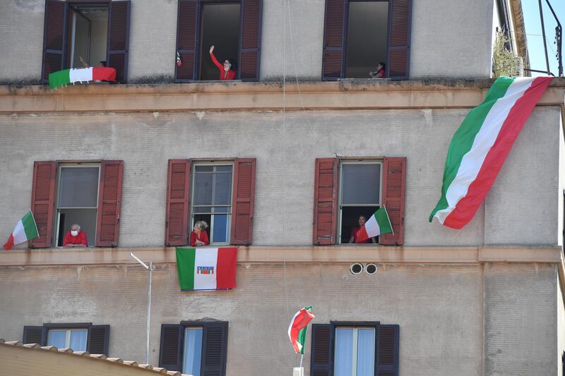 Residents with Italian flags in the Garbatella district of Rome take part on April 25, 2020 in a 'Liberation Day' flashmob with people singing Italian partizan song 'Bella Ciao' from their window or balcony, during the country's lockdown aimed at curbing the spread of the COVID-19 infection, caused by the novel coronavirus. (Photo by Tiziana FABI / AFP)
