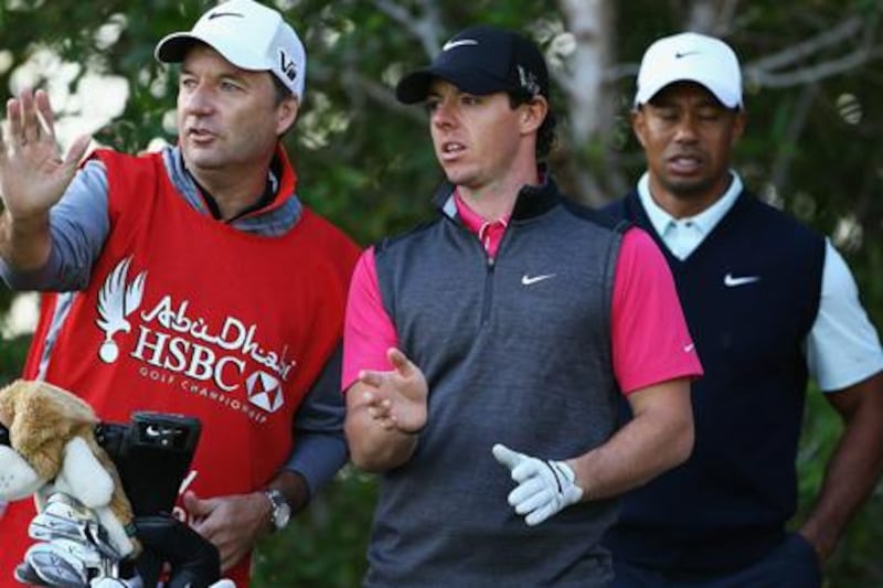 Rory McIlroy consults with caddie JP Fitzgerald while Tiger Woods looks on during day one of the Abu Dhabi HSBC Golf Championship.