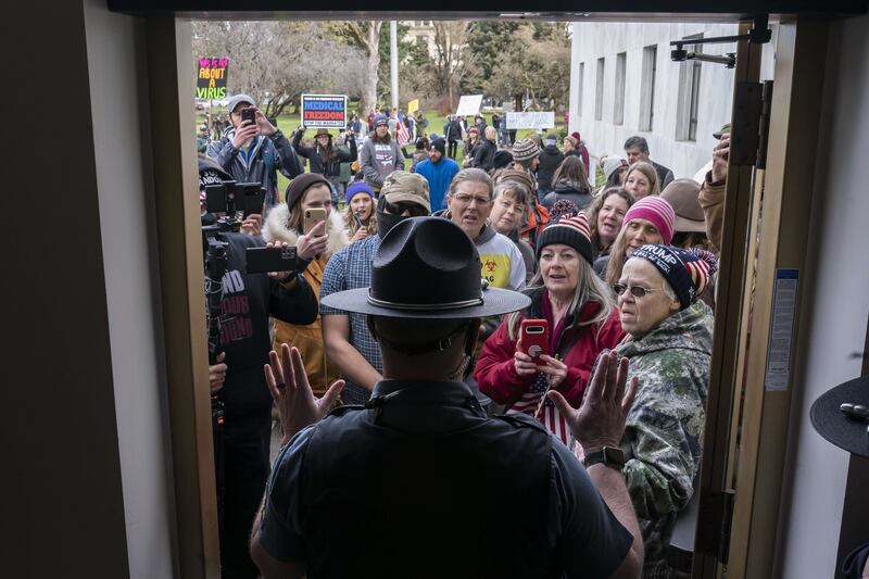 Protesters argue with state troopers i Oregon, US, as they try to get into a rally against coronavirus restrictions in Salem's state capitol building without wearing face masks. Getty