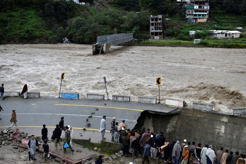 People forced from their homes gather at a road damaged by flood waters following monsoon rains in the Madian area of Pakistan's northern Swat Valley. AFP