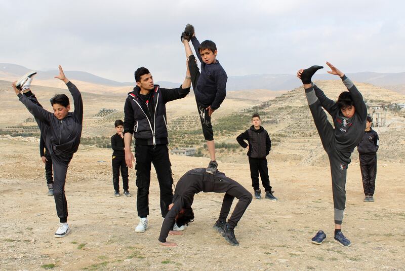 Young Syrian martial artists stretch during a training session.