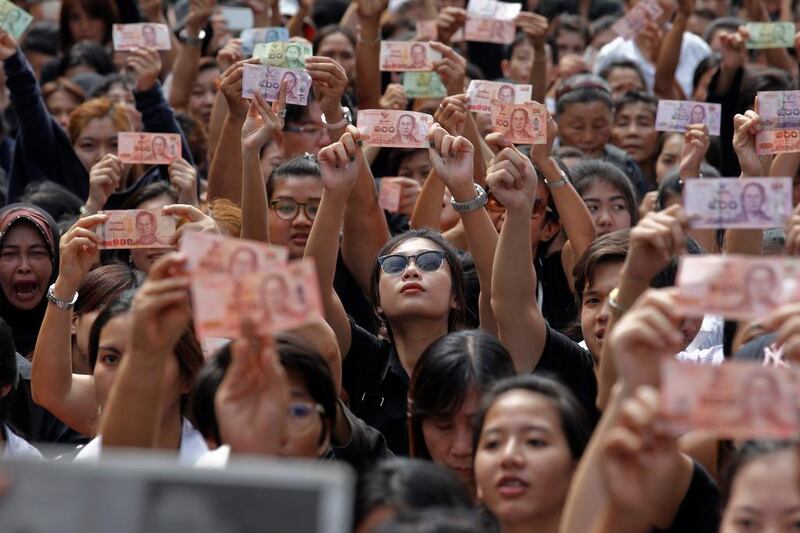 Mourners hold up Thai baht banknotes displaying the late King Bhumibol's portrait as his body is moved from the Bangkok hospital, where he died, to the Grand Palace in Bangkok on October 14, 2016. Chaiwat Subprasom / Reuters