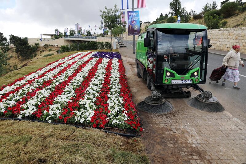 A street sweeper cleans the sidewalk next to a flower bed in the shape of a US flag, near the location of the new US embassy in Jerusalem, on May 13, 2018. Ammar Awad / Reuters