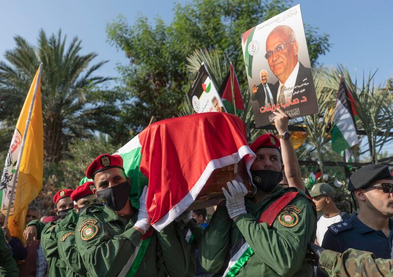 A Palestinian honor guard carries the body of Saeb Erekat into the cemetery during his funeral in the West Bank town of Jericho, Wednesday, Nov. 11, 2020. Erekat, a veteran peace negotiator and prominent international spokesman for the Palestinians for more than three decades, died on Tuesday, weeks after being infected by the coronavirus. He was 65. (AP Photo/Nasser Nasser)