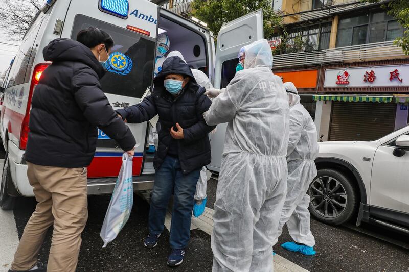 Fully protected medical staff help a patient off the ambulance outside the hospital in Wuhan, Hubei province, China.  EPA
