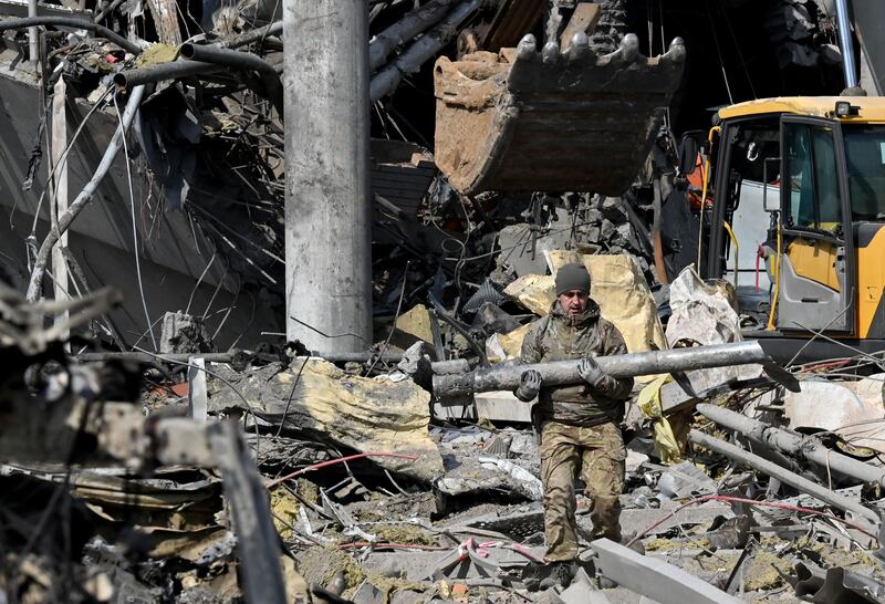 A Ukrainian serviceman carries a fragment of a rocket outside a building in Kyiv that was destroyed by Russian shelling. AFP