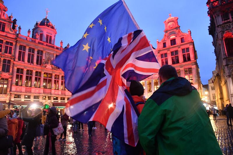 Pedestrians wave European Union (EU) and British Union flags in Grand Place square in Brussels, Belgium, on Thursday, Jan. 30, 2020. The European Parliament approved Prime Minister Boris Johnson’s Brexit deal, clearing the way for the U.K. to leave the EU on Jan. 31 with an agreement that, for the time being, will avoid a chaotic rupture. Photographer: Geert Vanden Wijngaert/Bloomberg