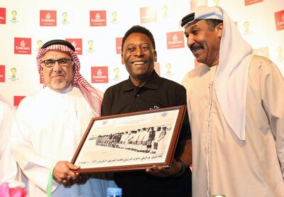 Pele receives photographs from when his Brazilian team Santos played Al Nasr in Dubai in 1973 during a 2013 visit to the UAE. Afsal Sham / Al Ittihad