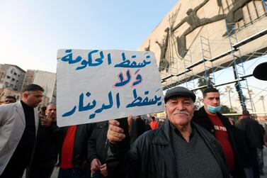 An Iraqi protester carries a placard denouncing the devaluation of the country's currency during a demonstration at Tahrir Square in central Baghdad, Iraq, on December 21, 2020. EPA