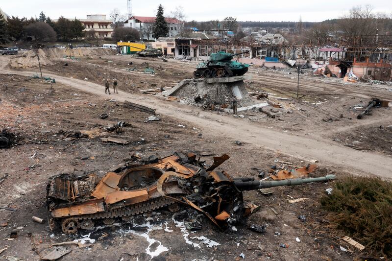Local residents pass by a destroyed Russian tank in the town of Trostyanets, east of capital Kyiv, Ukraine.  The monument to the Second World War is seen in background. AP Photo