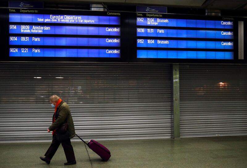 A traveller walks with a suitcase past an information board at the Eurostar terminal at St Pancras International, as EU countries impose a travel ban from the UK following the coronavirus disease (COVID-19) outbreak, in London, Britain, December 21, 2020. REUTERS/Hannah McKay