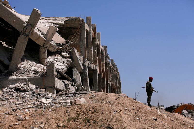 FILE PHOTO: A member of Syrian forces of President Bashar al Assad stands guard near destroyed buildings in Jobar, eastern Ghouta, in Damascus, Syria April 2, 2018. REUTERS/Omar Sanadiki/File Photo