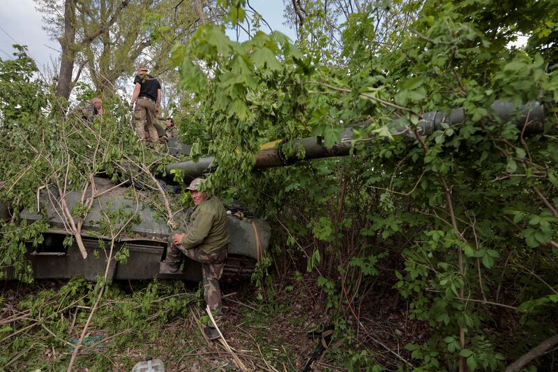 Ukrainian servicemen are seen near a T-80 tank captured from Russian troops in Kharkiv region. Reuters