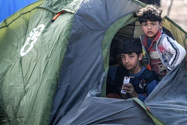 Migrant children sit in a shelter near the Tunca river as they wait to resume their efforts to enter Europe near Pazarkule border gate in the city of Edirne, northwest Turkey on March 5, 2020. - EU members on March 4, 2020 rejected what they said is Turkey's use of desperate migrants to pressure its neighbours -- and strongly backed Greece's border crackdown. The EU has scrambled to respond to the surge of migrants at the Greek border, where authorities say some 24,000 were stopped from entering between February 29 - March 2, 2020. (Photo by Ozan KOSE / AFP)
