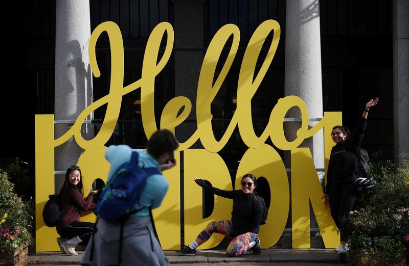 People pose for a picture next to a sign at Covent Garden in London. Reuters