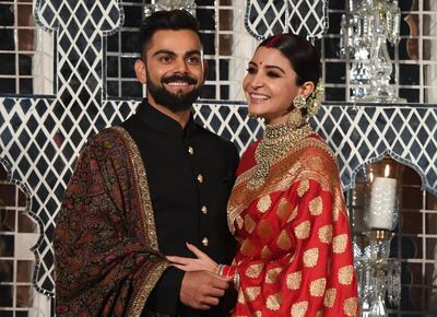 (FILES) In this file photo taken on December 22, 2017 Indian cricketer Virat Kohli (L) and Bollywood actress Anushka Sharma, who were recently married in Italy, pose during a reception in New Delhi. Virat Kohli having his hair cut by his Bollywood wife, to Ravindra Jadeja on a stallion, India's superstar cricketers are making the most of their enforced break during the national coronavirus lockdown. The Indian government imposed a 21-day lockdown on March 24, 2020, as a preventive measure against the spread of the COVID-19 novel coronavirus. / AFP / Prakash SINGH
