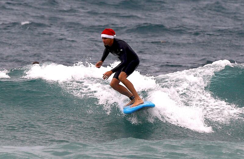 A surfer wearing a Christmas hat rides a wave on his surfboard on Christmas Day at Sydney's Bondi Beach in Australia on December 25, 2017. David Gray / Reuters