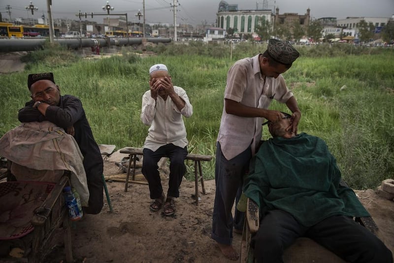 A Uighur barber shaves a customer in old Kashgar city before the Eid holiday on July 28, 2014, in China’s Xinjiang province, where nearly 100 people were killed in unrest recently. Kevin Frayer / Getty Images