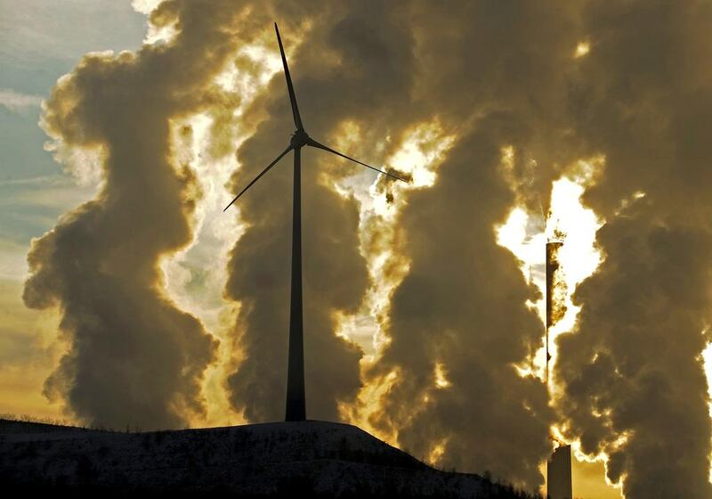 A wind turbine in front of a steaming coal power plant in Gelsenkirchen, Germany. A UN report said that countries must cust spending on fossil-powered plants by $30 billion by 2030. Martin Meissner / AP Photo