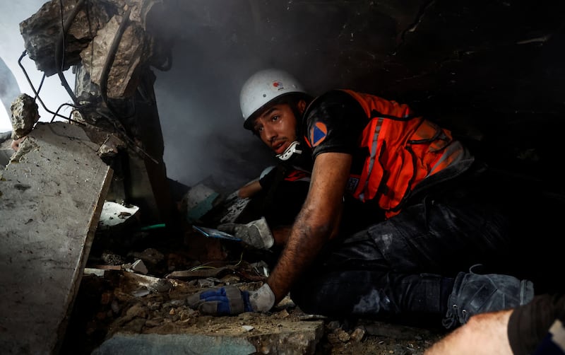 A rescue worker searches for casualties under the rubble of a building in Khan Younis. Reuters
