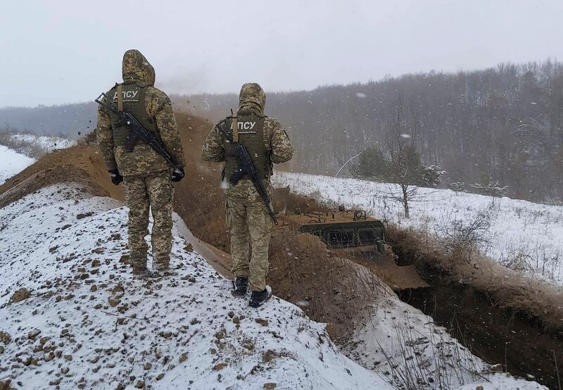 Ukrainian border guards watch as a special vehicle digs a trench on the Ukraine-Russia border close to Sumy. AP