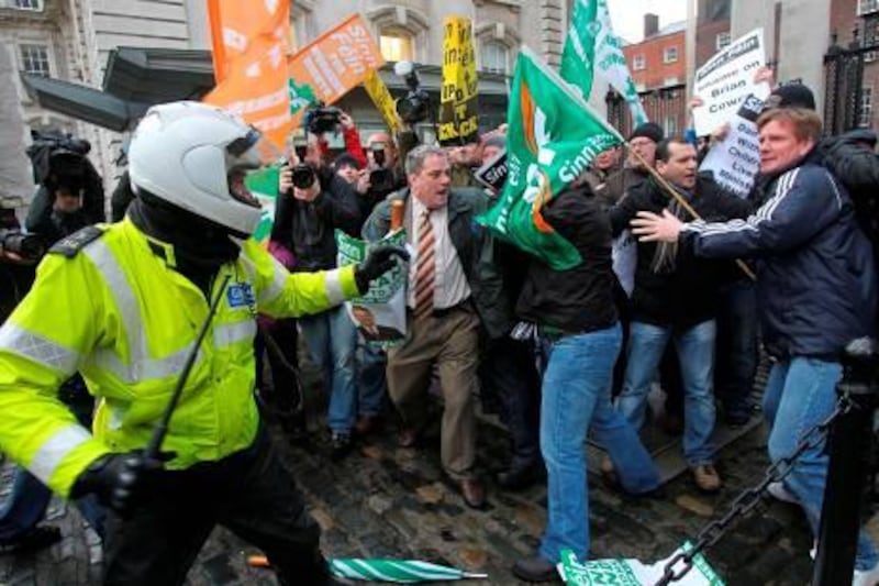 An Irish policeman (L) is confronted by protestors as they break through the front gates of the Irish Prime Ministers office in Dublin, Ireland, on November 22, 2010. Ireland was Monday hammering out the conditions of an EU bailout package worth up to 90 billion euros, sending the single currency soaring but sparking fierce criticism at home of the already beleaguered government. AFP PHOTO/Peter Muhly
 *** Local Caption ***  716588-01-08.jpg