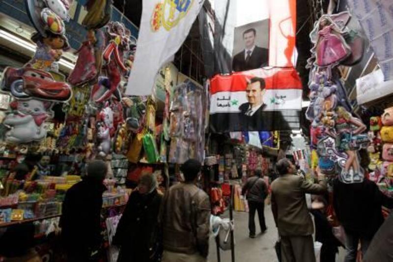 A Syrian flag with portraits of Syrian President Bashar Assad decorate the street scene as shoppers look of souvenirs in Damascus, Syria, on Saturday Feb. 5, 2011.  An internet campaign calling for "a day of rage" on Friday and now Saturday Feb. 5, against Syrian authorities seems to have failed to attract dissenters onto the streets of Damascus. There are alleged reports that police have intimidated anyone who tried to assemble on the streets over recent days, but there is no sign of the mass protests which have swept Egypt over recent days. (AP Photo/Hussein Malla) *** Local Caption ***  XHM103_Mideast_Syria_Protests.jpg