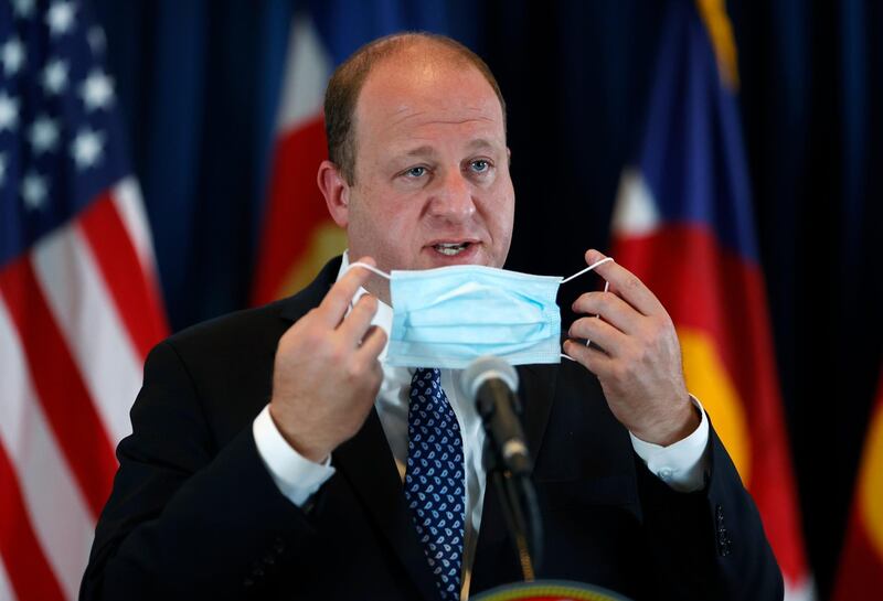 Colorado Governor Jared Polis puts on his face mask after a news conference about the state's efforts to cut the spread of the coronavirus in Denver this week. AP Photo