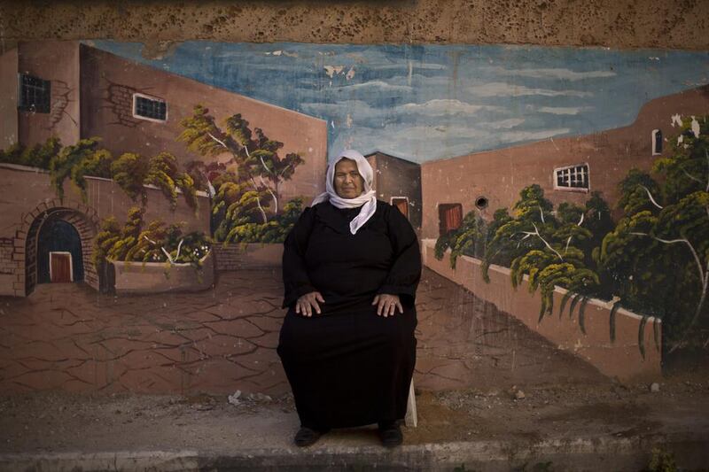 Palestinian refugee Jamilah Shalabi, 70, in front of a wall painted with a mural in the West Bank refugee camp of Jenin, where she has lived since she was 4 years old when she and her parents were forced to leave their home in Zarin village.
