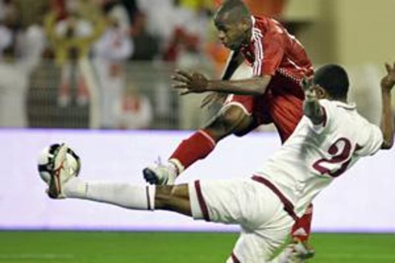 Hassan Rabia, in red, slams the ball home as the Qatar defender Mussa Haroun tries in vain to block the shot.
