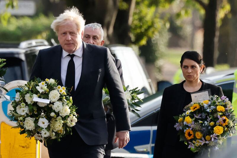 UK Prime Minister Boris Johnson and Home Secretary Priti Patel carry floral tributes to the scene of the fatal stabbing of Conservative lawmaker David Amess in south-east England on Saturday. AFP