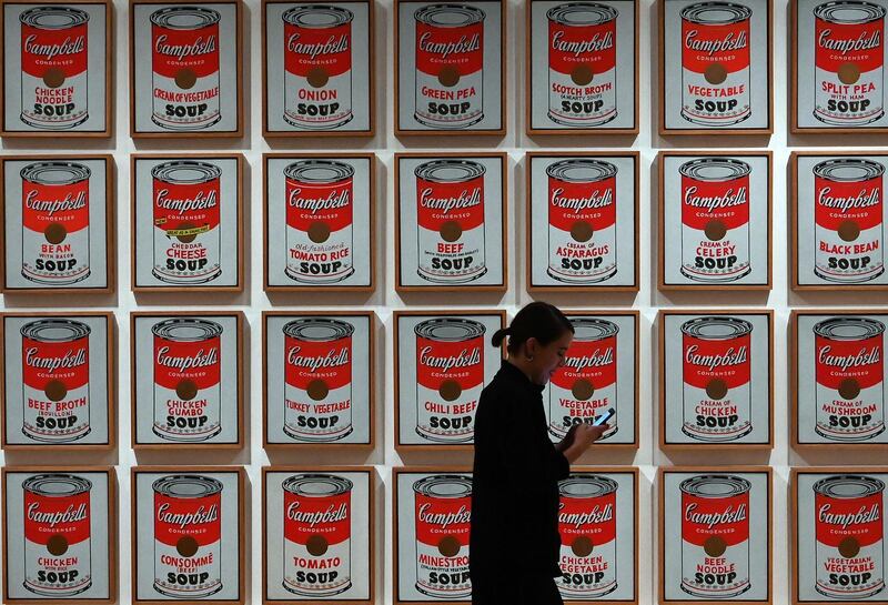 A woman walks past Andy Warhol's "Campbell's Soup Cans." AFP