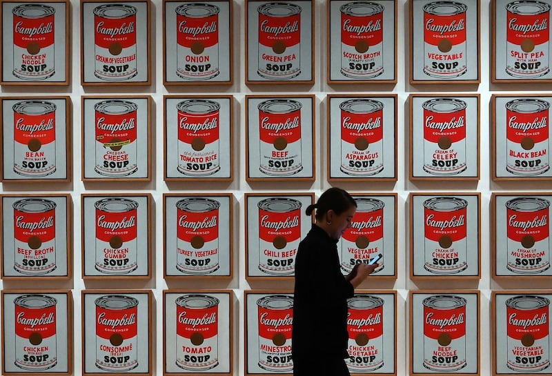 A woman walks past Andy Warhol's "Campbell's Soup Cans." AFP