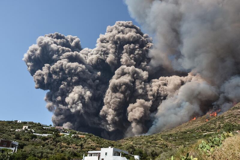 Smoke billows and flammes propaqate accross the hillside neqr houses after the Stromboli volcano erupted on the Stromboli island, north of Sicily. A volcano on the Italian island of Stromboli erupted dramatically killing a hiker and sending tourists fleeing into the sea.  AFP