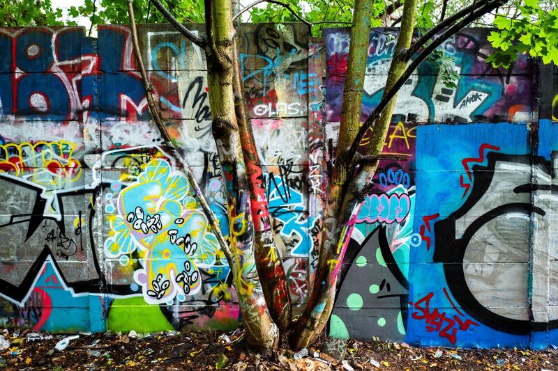 Graffiti art covers the hidden leftover segment of a back-wall of the Berlin wall, in Berlin's Pankow district on September 28, 2019. - Various associations in Berlin are keen to preserve lesser-known traces of the Berlin wall (1961-89), including segments of the back-wall, watch-towers and markers, in a bid to keep the memories of a divided Germany alive for future generations. (Photo by John MACDOUGALL / AFP)