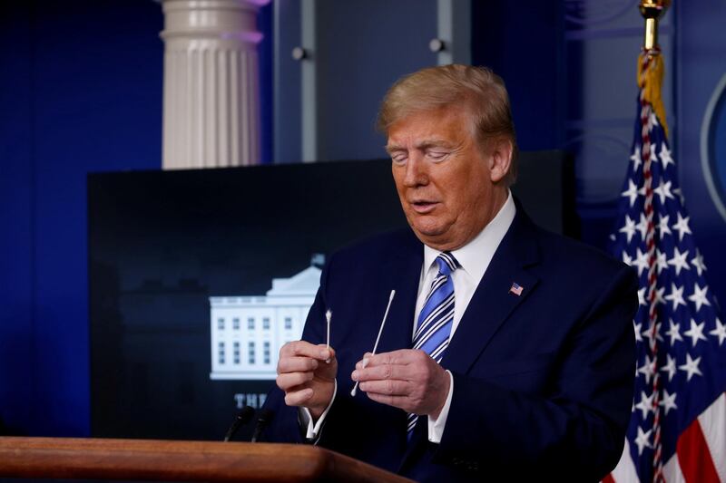 US President Donald Trump compares a swab for coronavirus disease testing with regular cotton swabs during the daily coronavirus task force briefing at the White House in Washington. Reuters